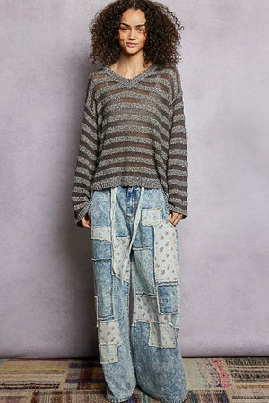 Woman wearing a striped sweater and patchwork jeans against a plain background