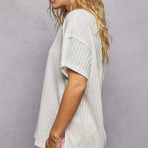 Woman wearing a light gray textured top against a plain background