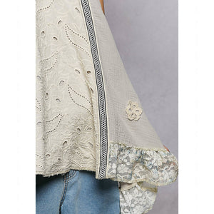 Light-colored lace top with floral details on a plain background