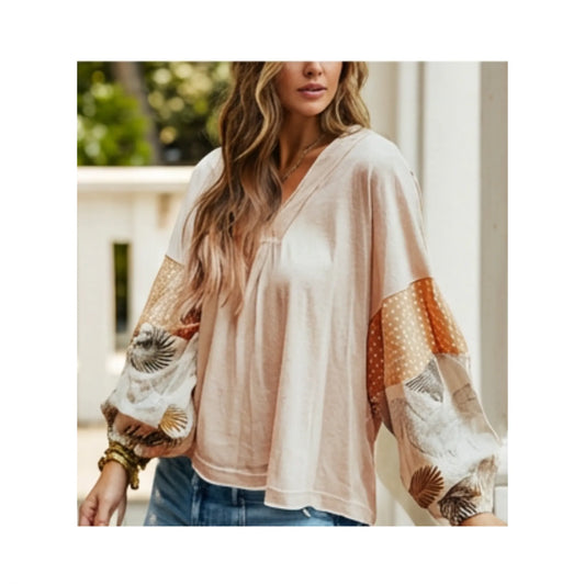 Woman wearing a beige blouse with patterned sleeves outdoors