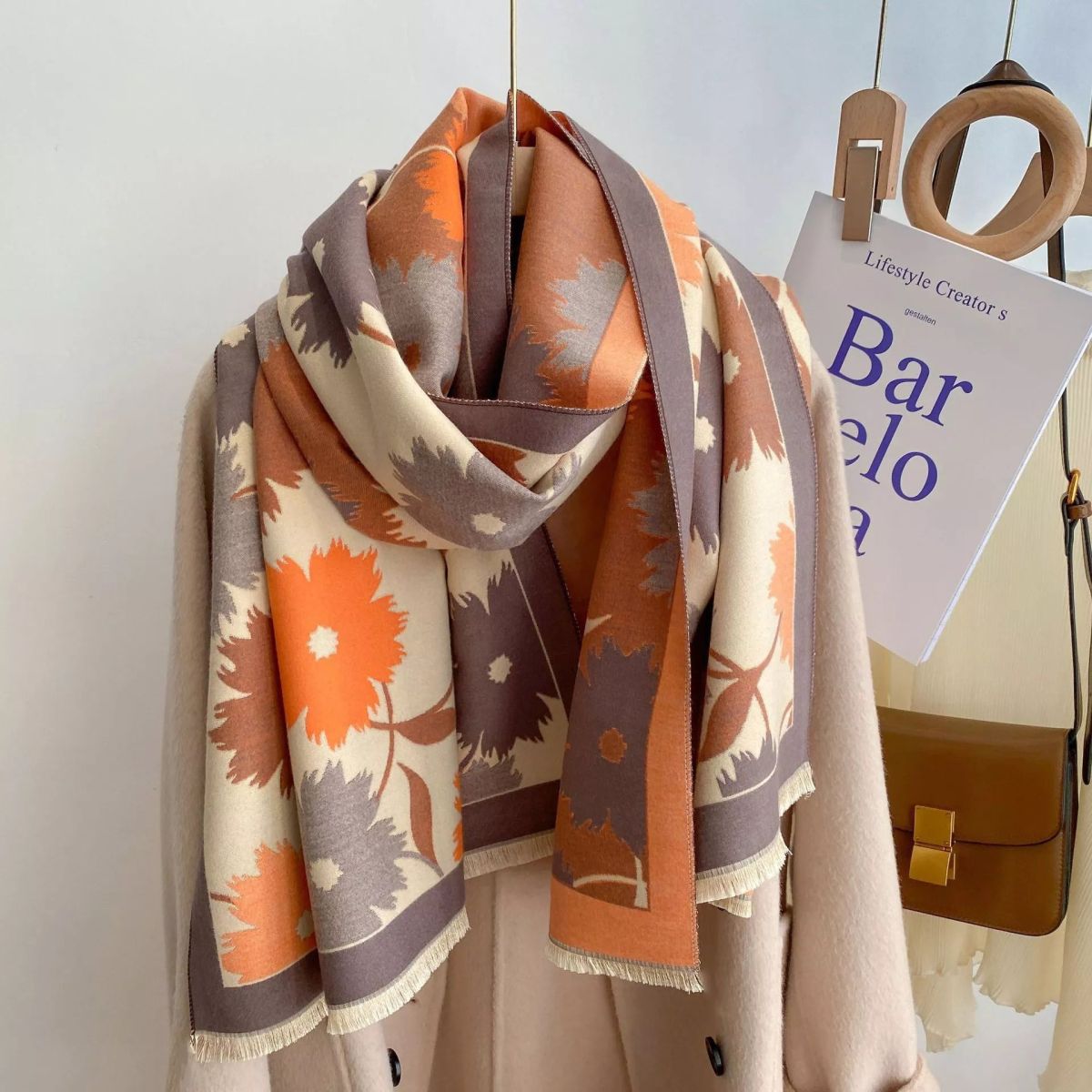 Floral patterned scarf draped over a chair with a magazine and handbag in the background.