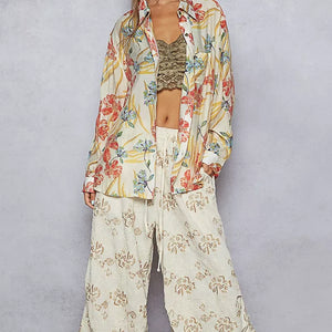 Person wearing a floral kimono and wide-leg pants on a plain background