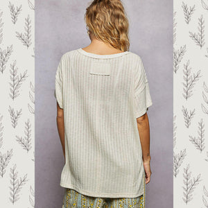 Person wearing a light-colored textured shirt with a neutral background