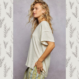 Woman wearing a light-colored top and patterned pants against a gray background with leaf designs.