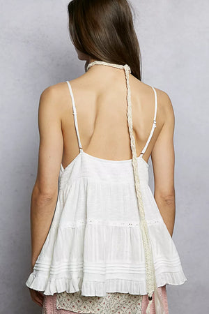 Woman wearing a white lace dress with thin straps against a gray background