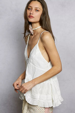 Woman wearing a white dress with thin straps against a plain background