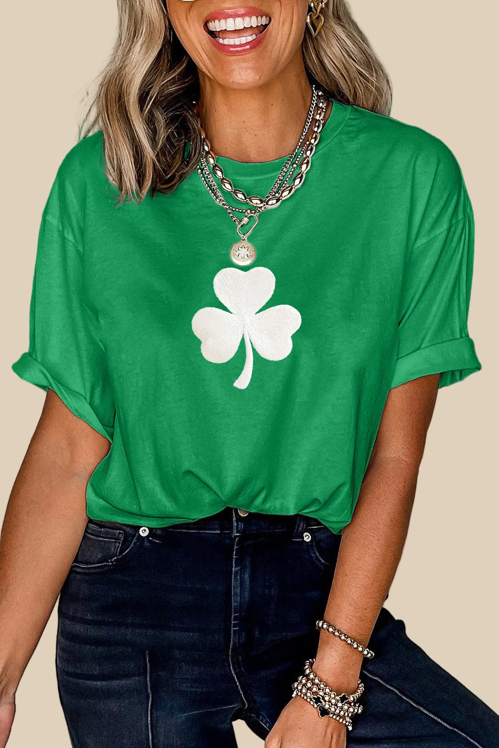 Person wearing a green t-shirt with a white shamrock design against a neutral background