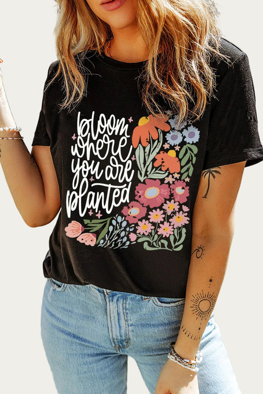 Person wearing a black t-shirt with floral design and text, standing outdoors.