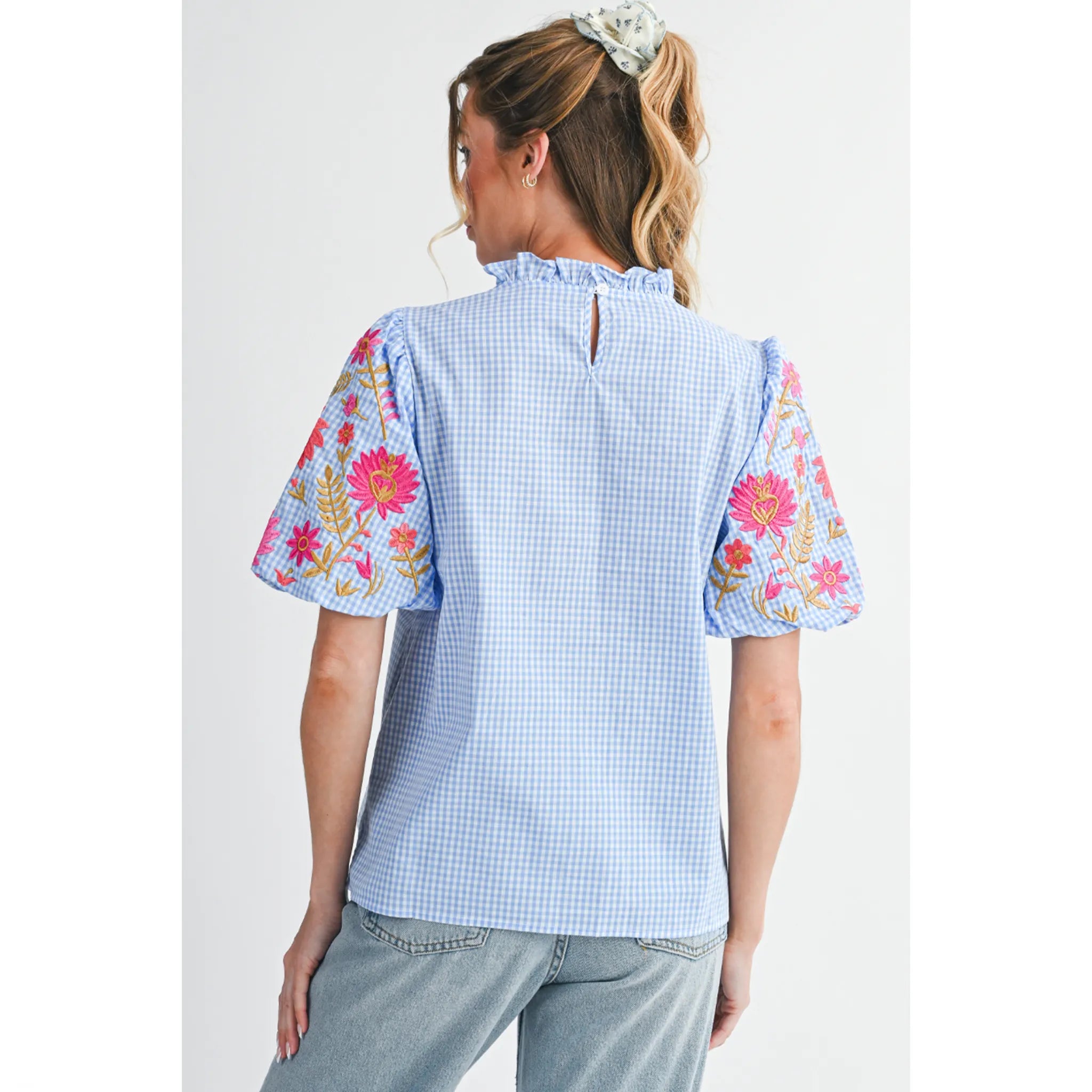 Woman wearing a blue checkered top with floral sleeves on a white background