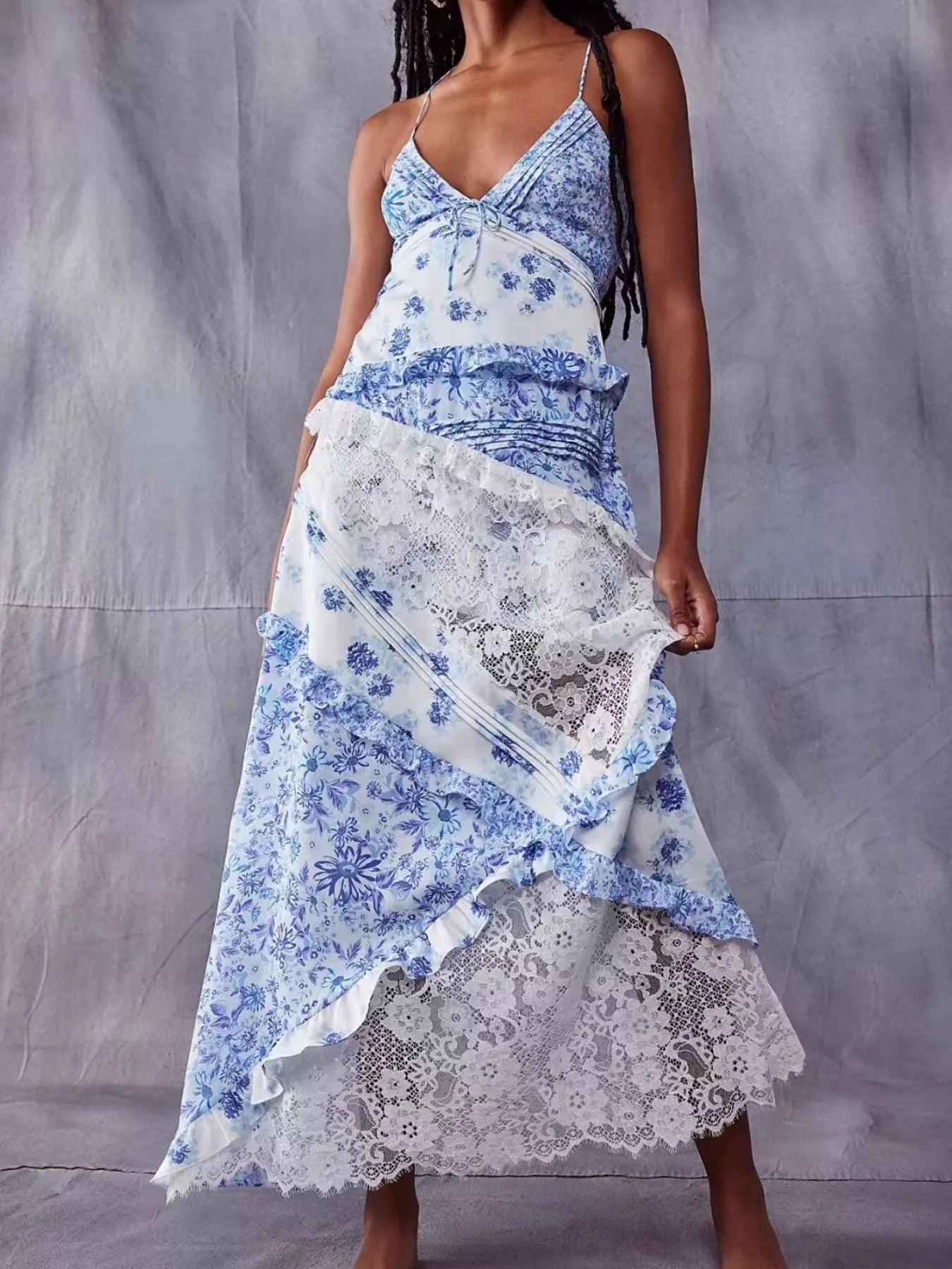 Woman wearing a blue and white floral dress with lace overlay against a gray background