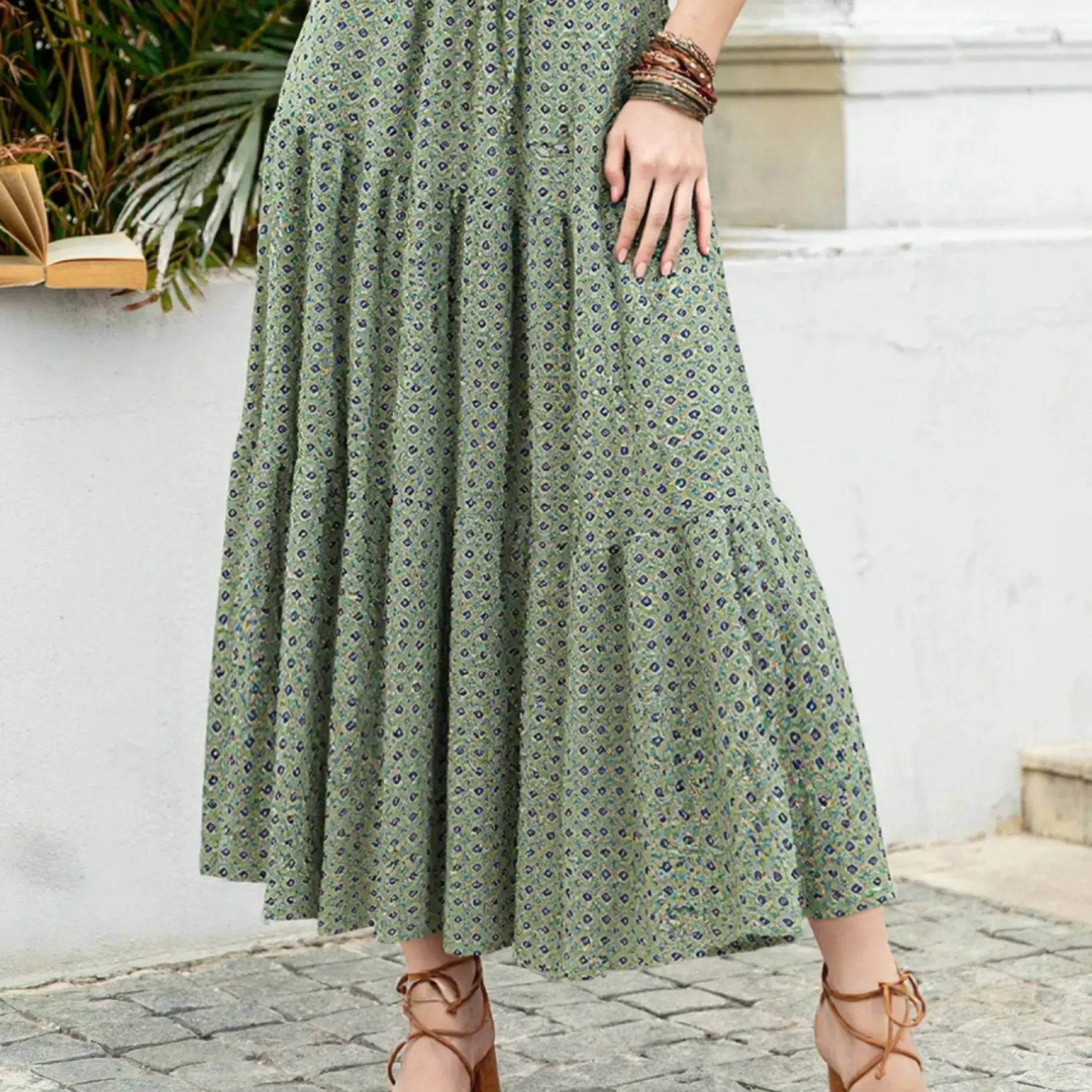 Person wearing a long green dress with a subtle pattern, standing outdoors.