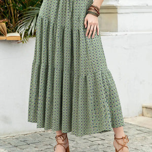 Person wearing a long green dress with a subtle pattern, standing outdoors.