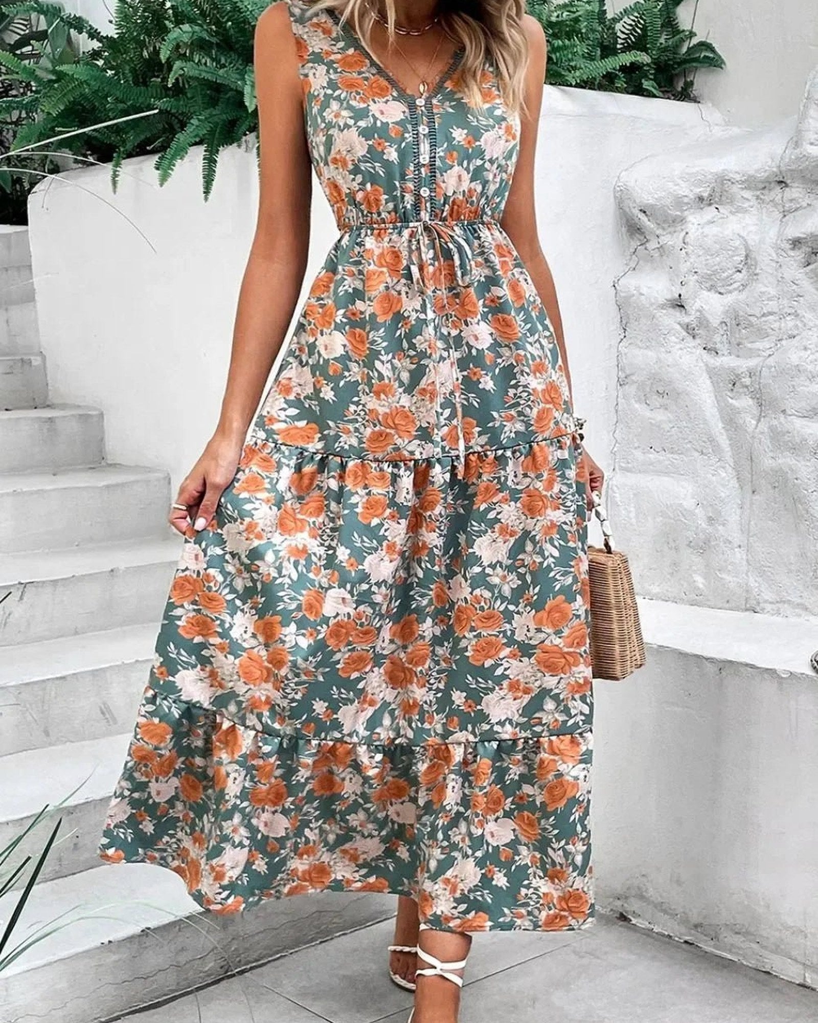 Woman wearing a floral dress standing on a white staircase.