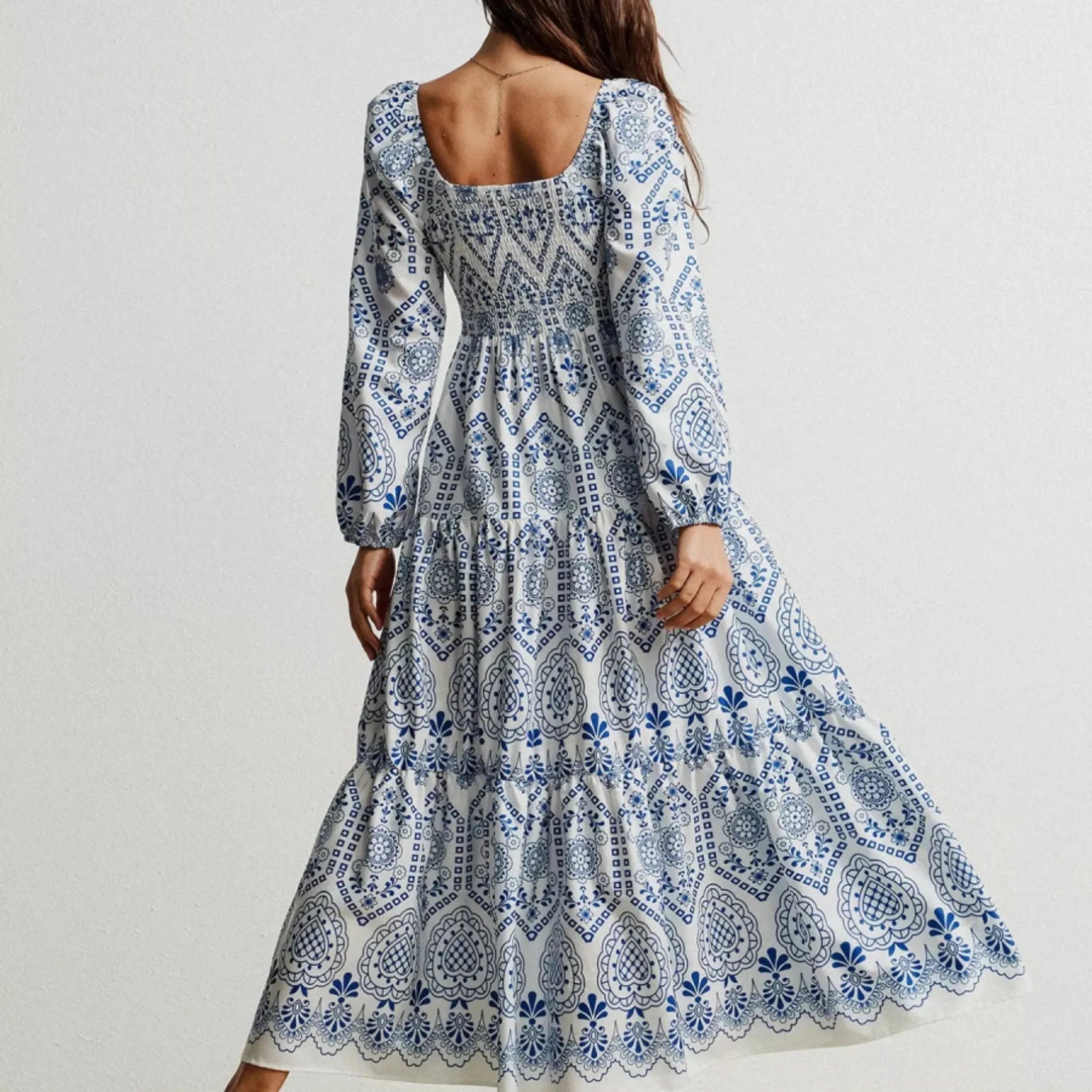 Woman wearing a blue and white patterned dress on a plain background