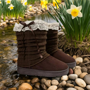 Brown winter boots with lace details on a pebble surface with flowers in the background