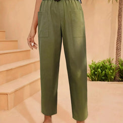 Green pants worn by a person on a peach-colored staircase with plants in the background