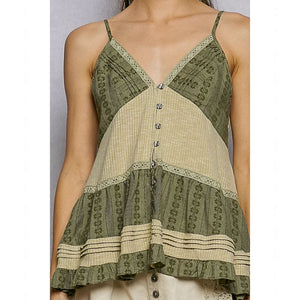 Green and beige patterned sleeveless top worn by a person on a plain background