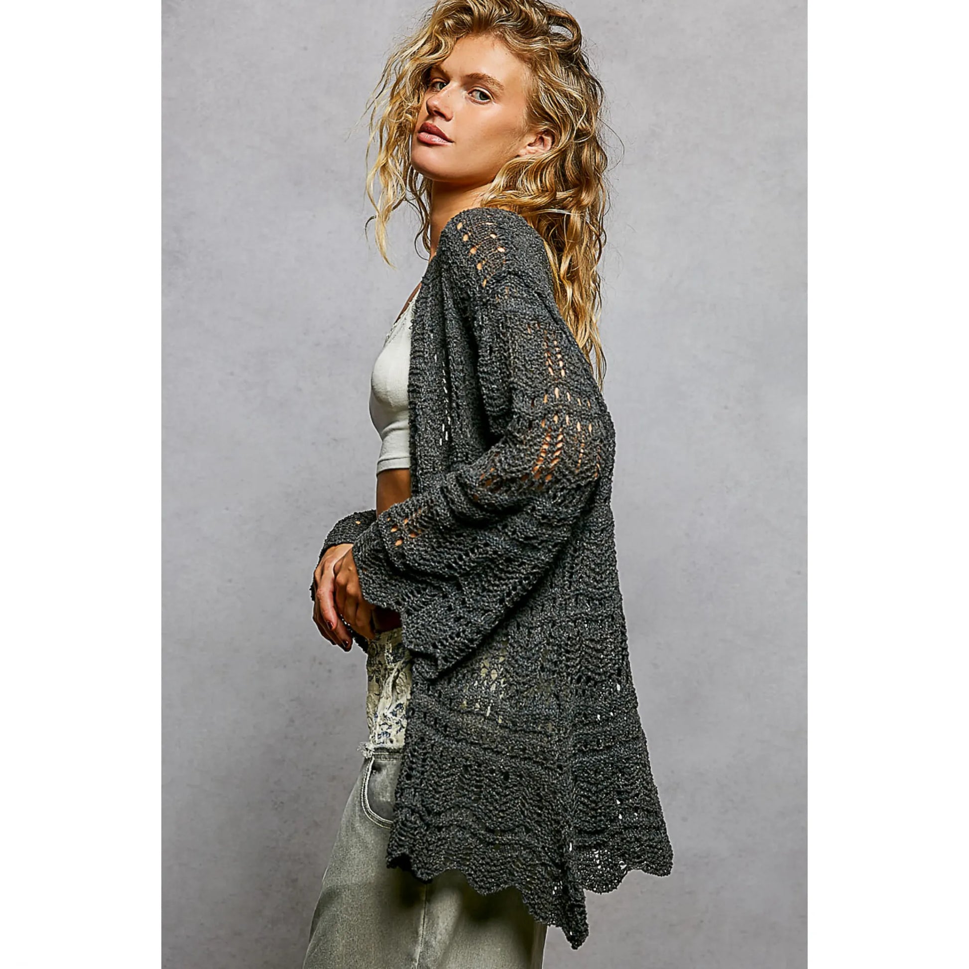 Woman wearing a dark gray knitted cardigan against a plain background