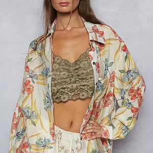 Woman wearing a floral blouse over a lace top on a plain background