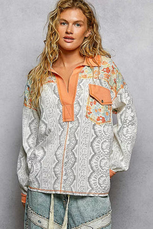 Woman wearing a patterned blouse with orange accents on a gray background