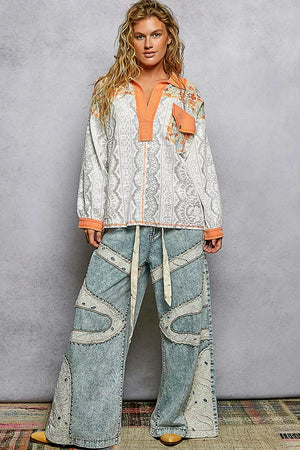 Woman wearing a patterned top and jeans against a gray background