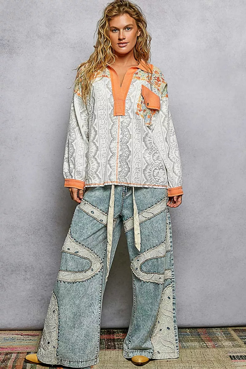 Woman wearing a patterned top and jeans against a gray background