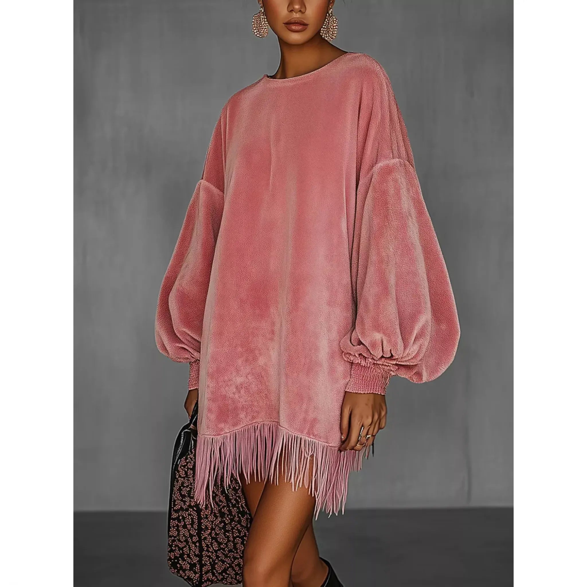 Pink velvet dress with fringes worn by a model against a gray background
