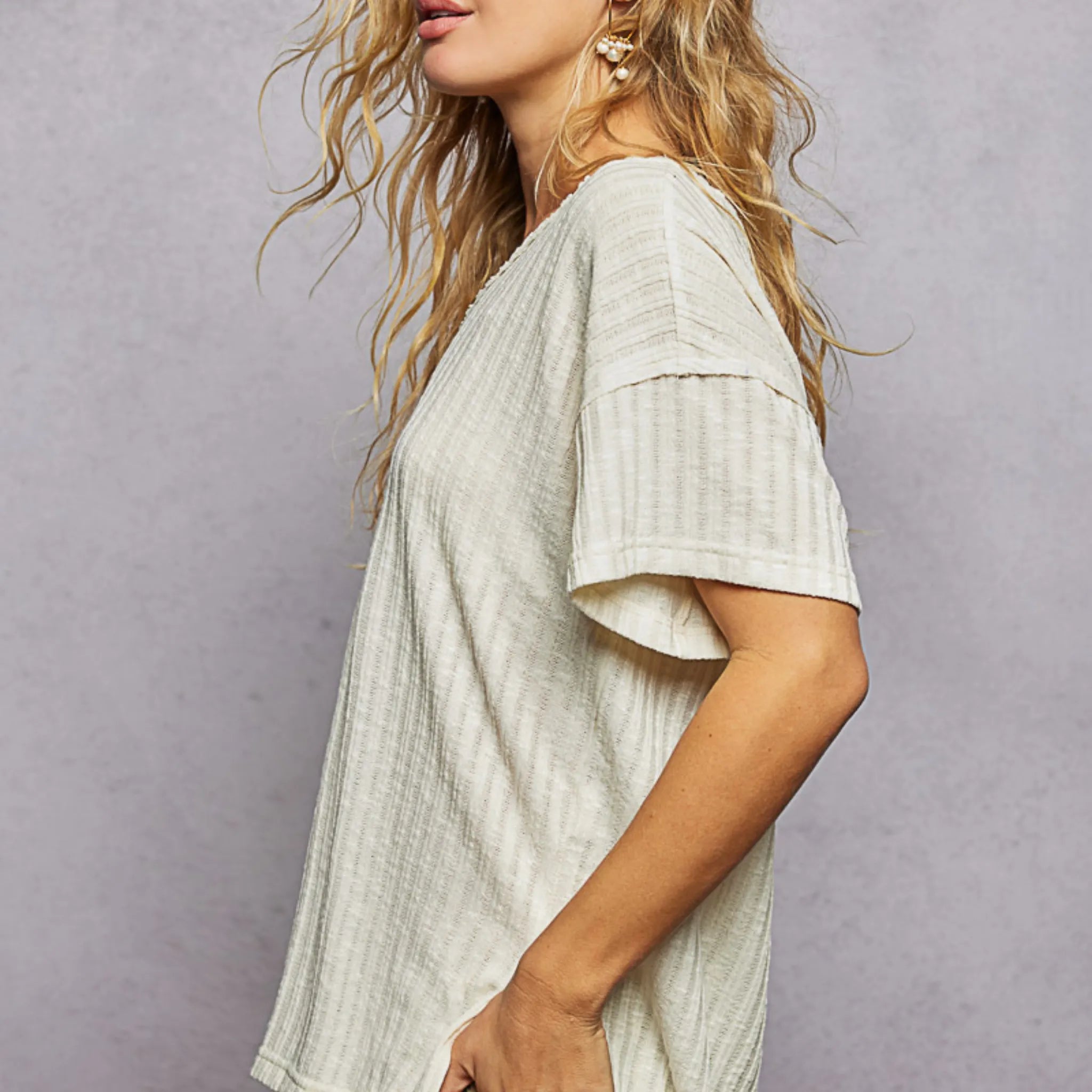 Woman wearing a light-colored textured top against a plain background