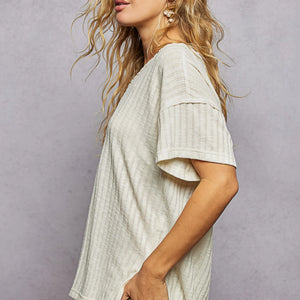 Woman wearing a light-colored textured top against a plain background