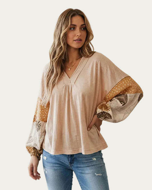 Woman wearing a beige blouse with patterned sleeves on a white background