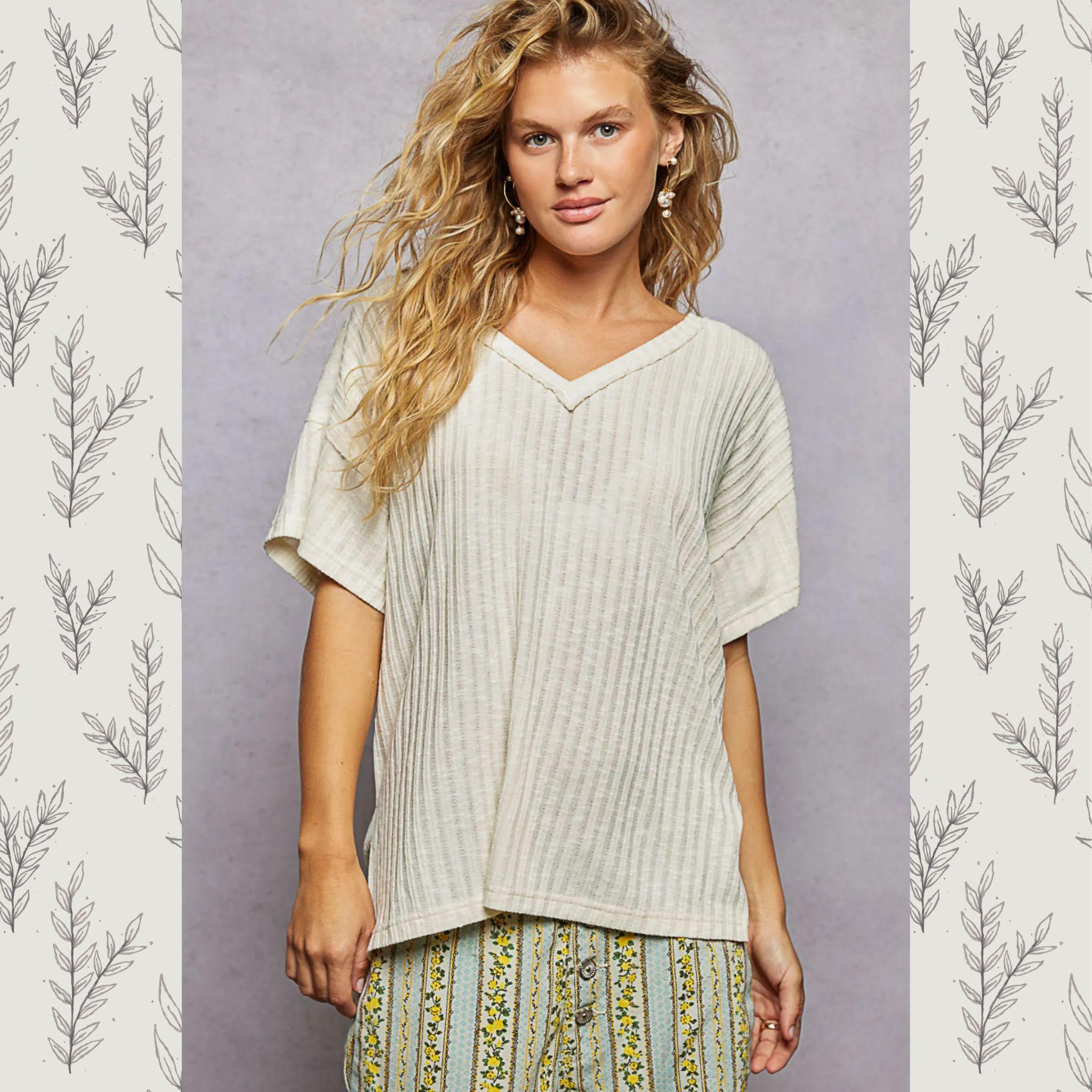 Woman wearing a light-colored ribbed top with a patterned skirt against a gray background