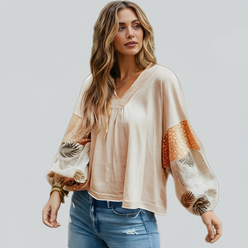 Woman wearing a beige blouse with patterned sleeves on a white background