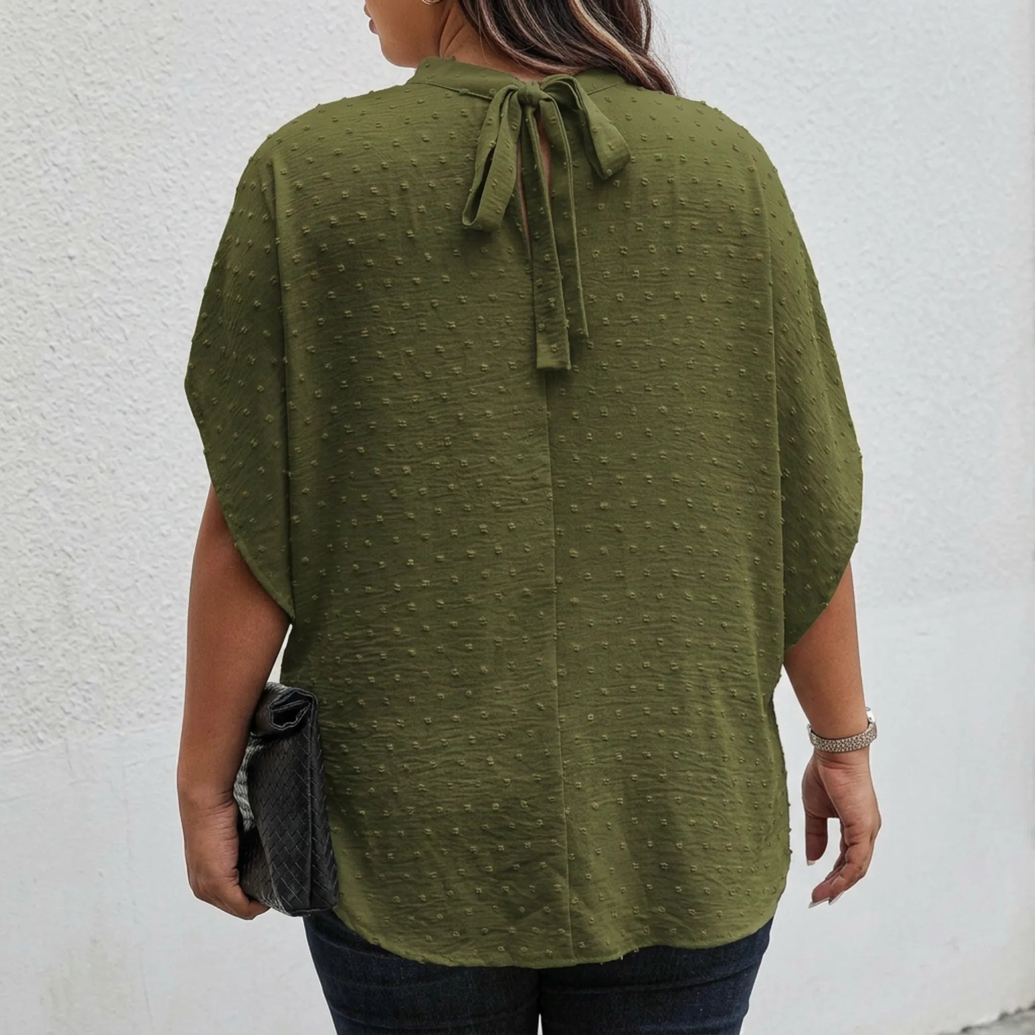 Person wearing a green blouse with a bow detail on a white background