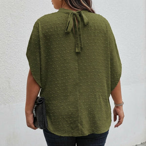 Person wearing a green blouse with a bow detail on a white background