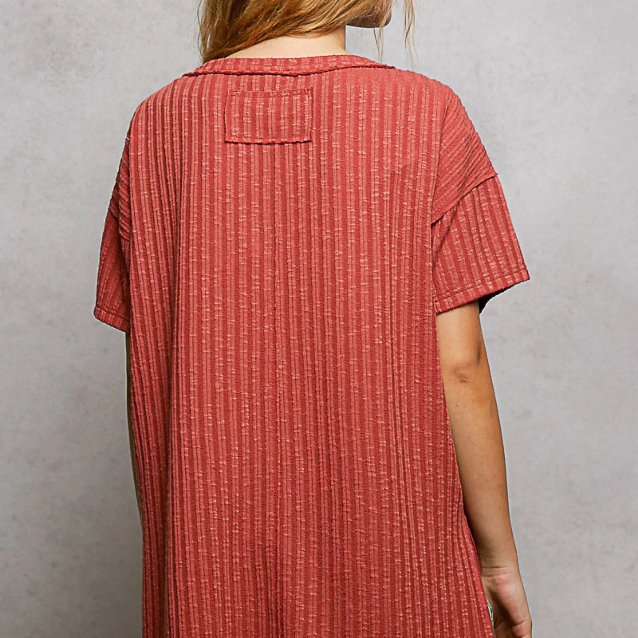 Person wearing a red textured dress against a gray background